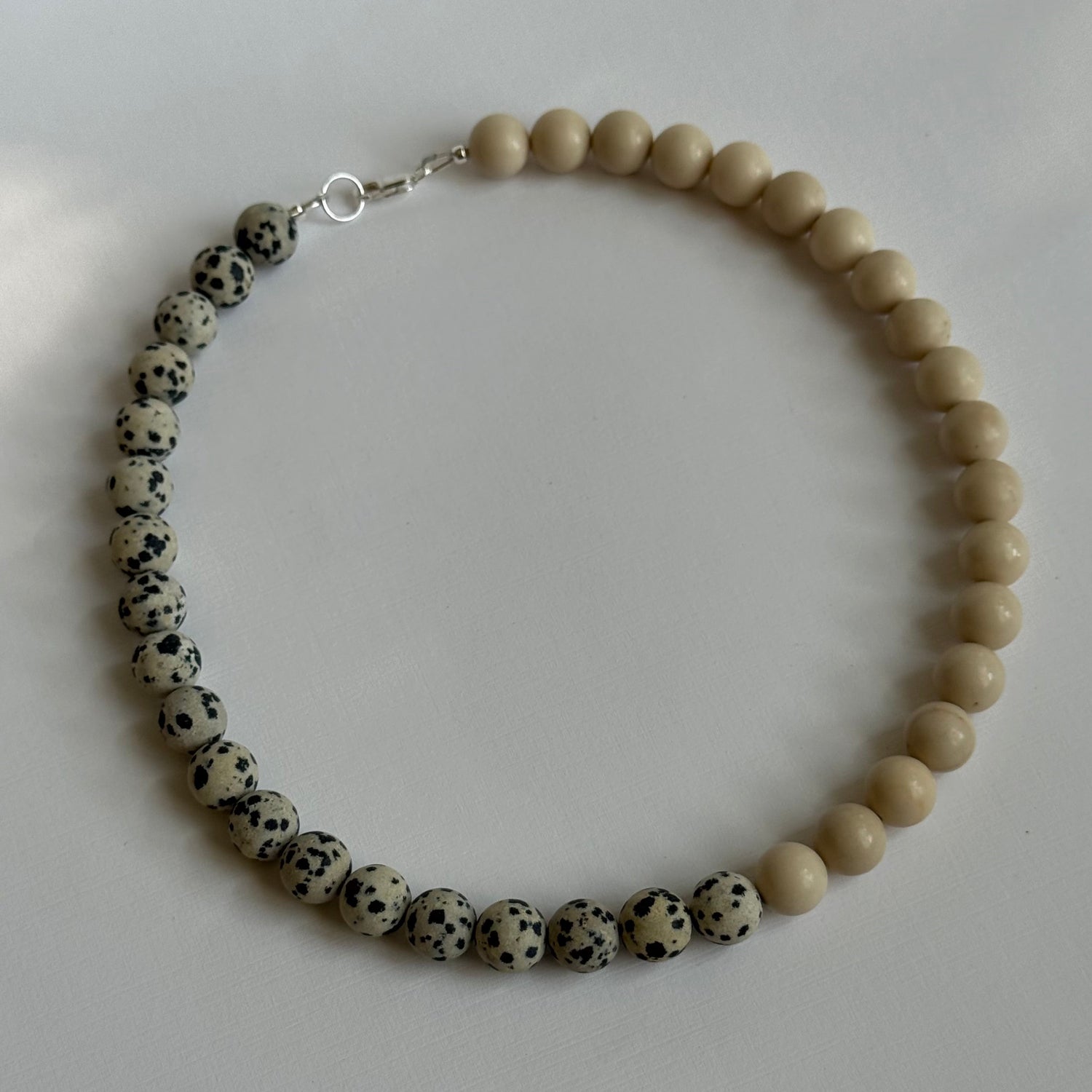 Necklace with alternating beige and black beads on a white background