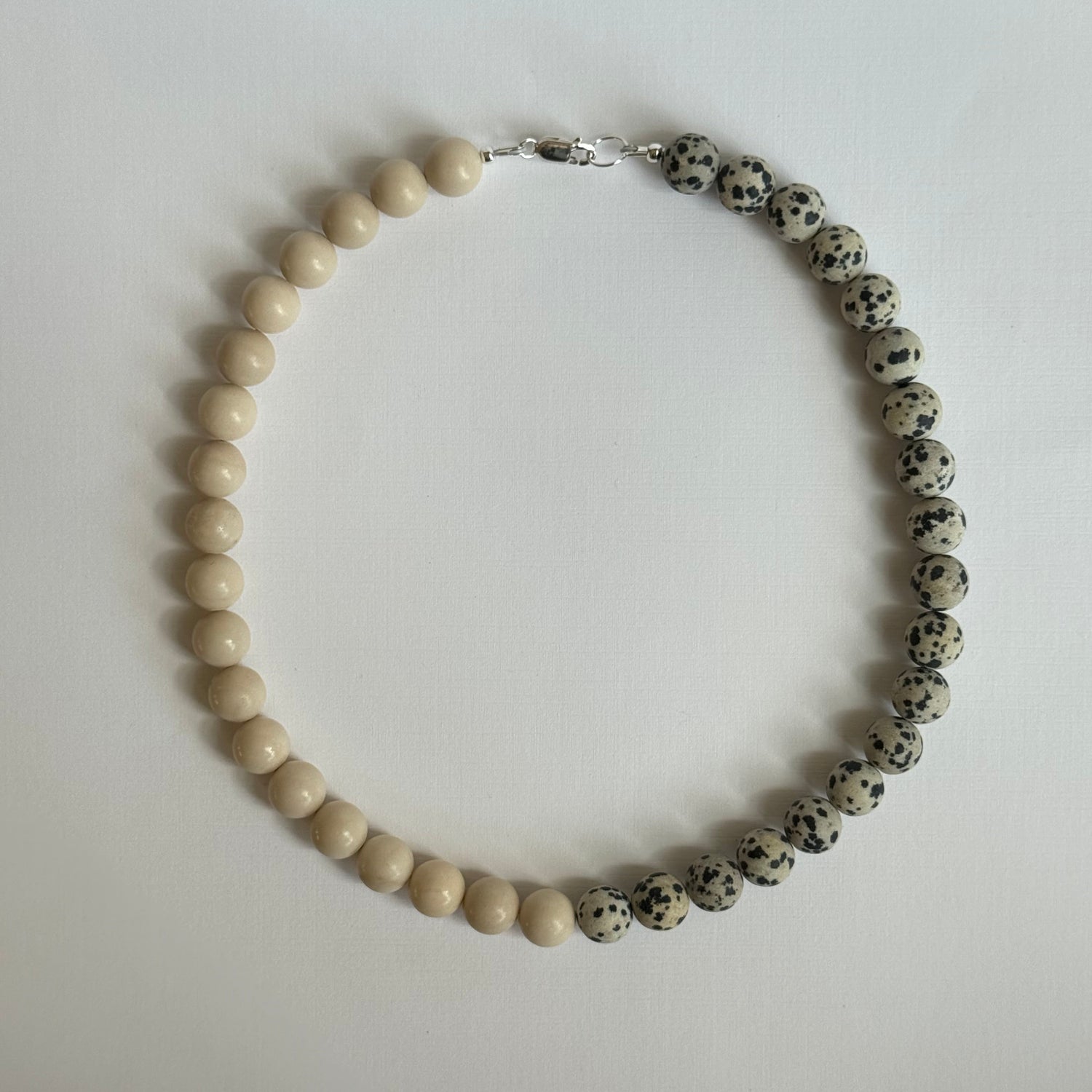 Necklace with alternating black and white beads on a light gray background