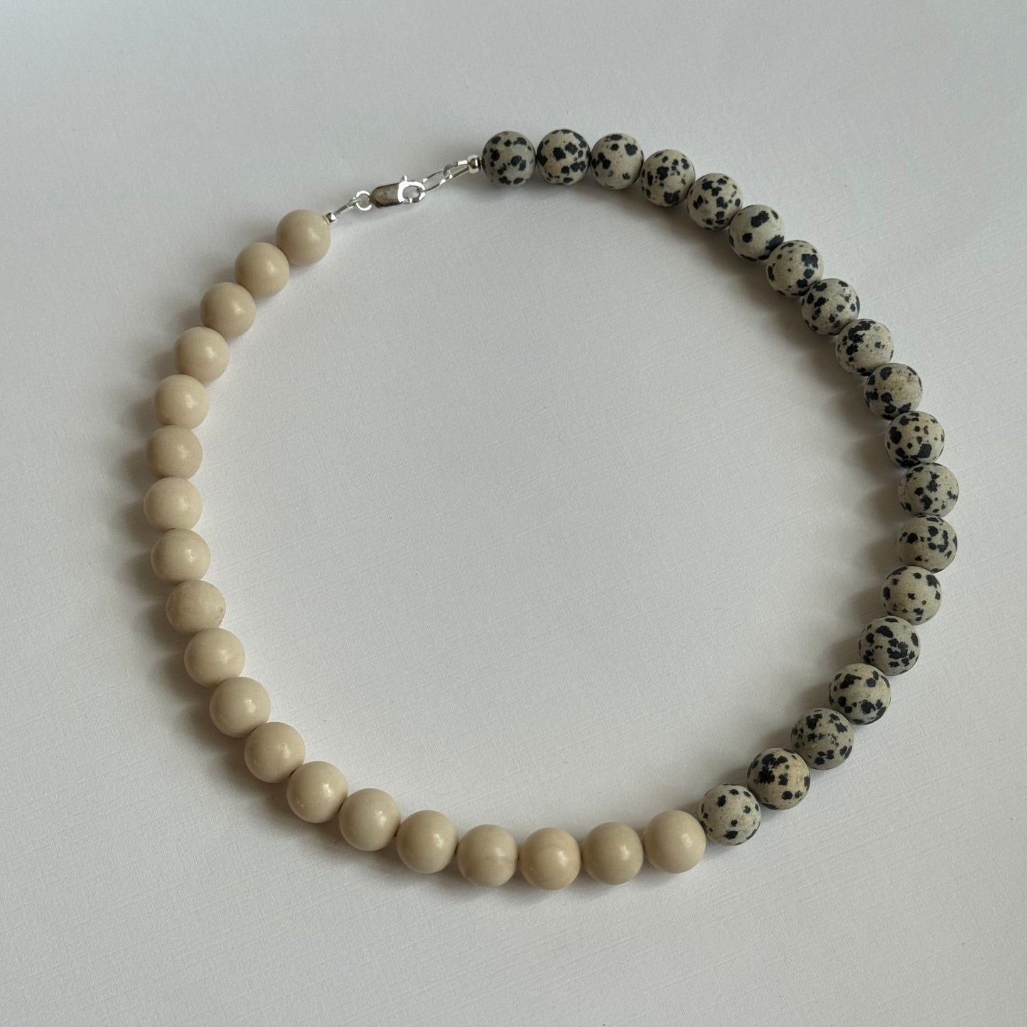 Necklace with alternating black and white beads on a light gray background