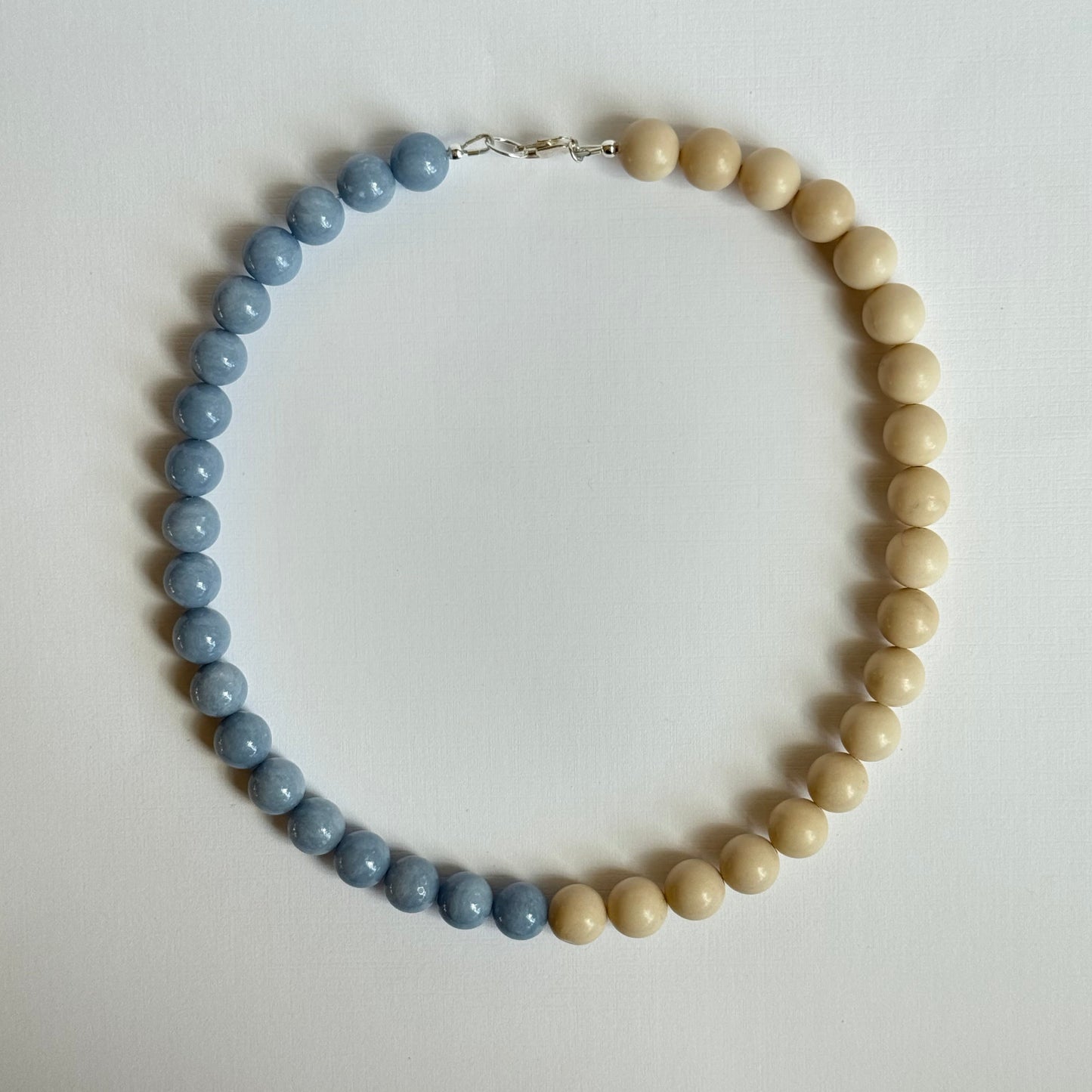 Necklace with alternating beige and blue beads on a light background