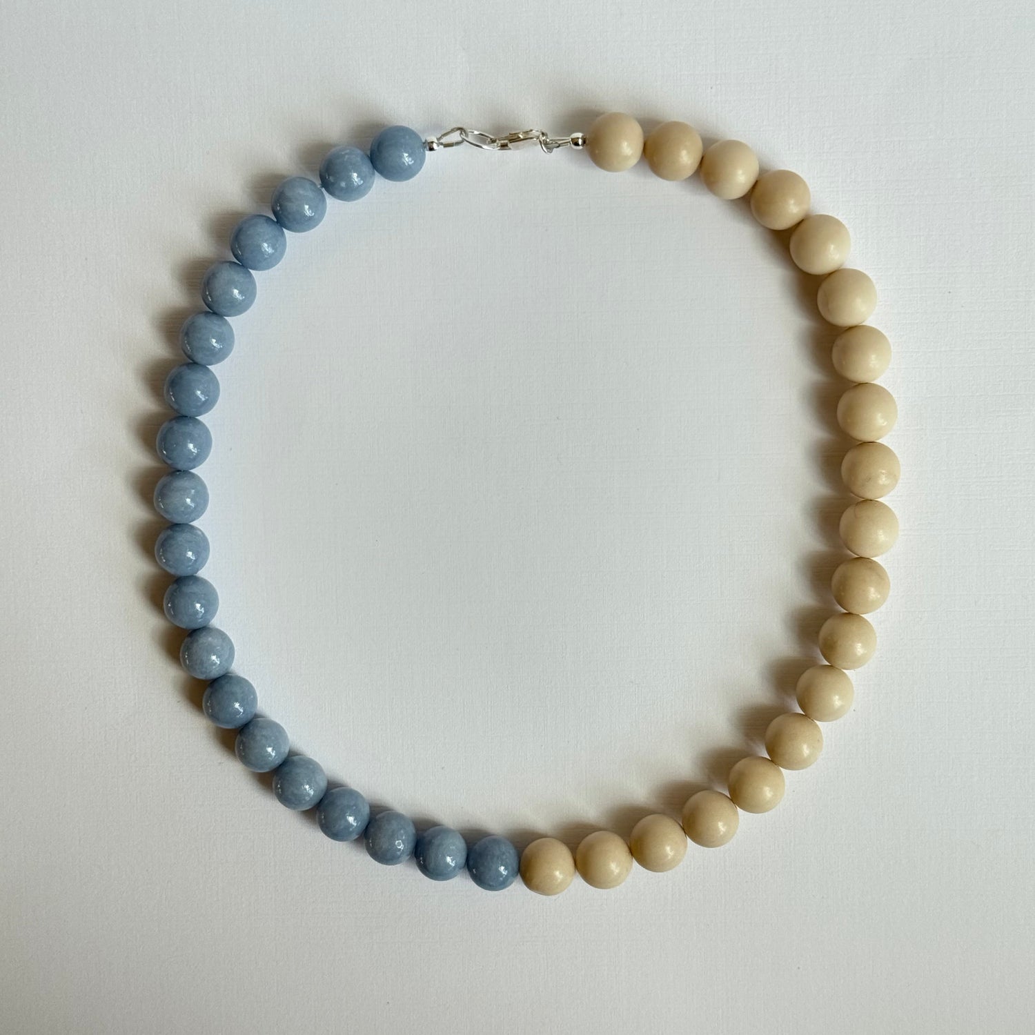 Necklace with alternating beige and blue beads on a light background