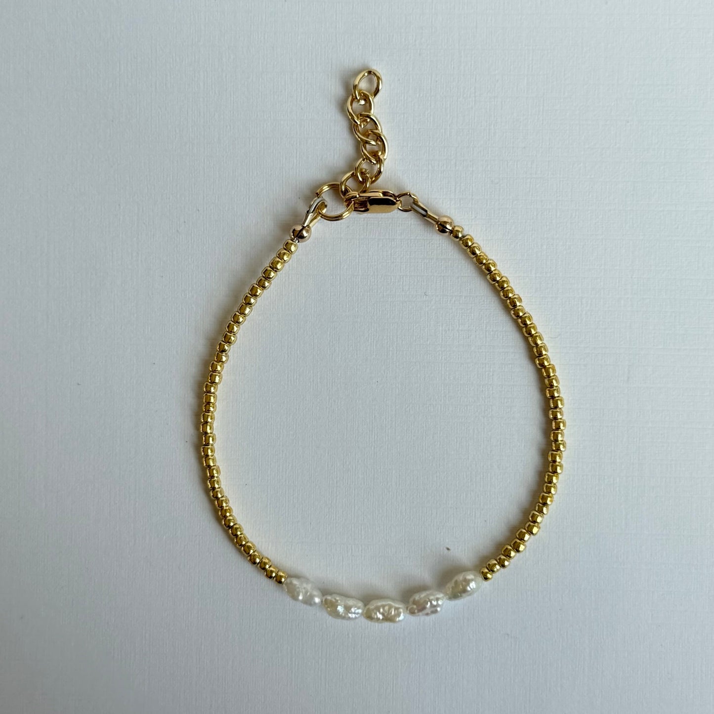 Gold bracelet with clear beads on a white background