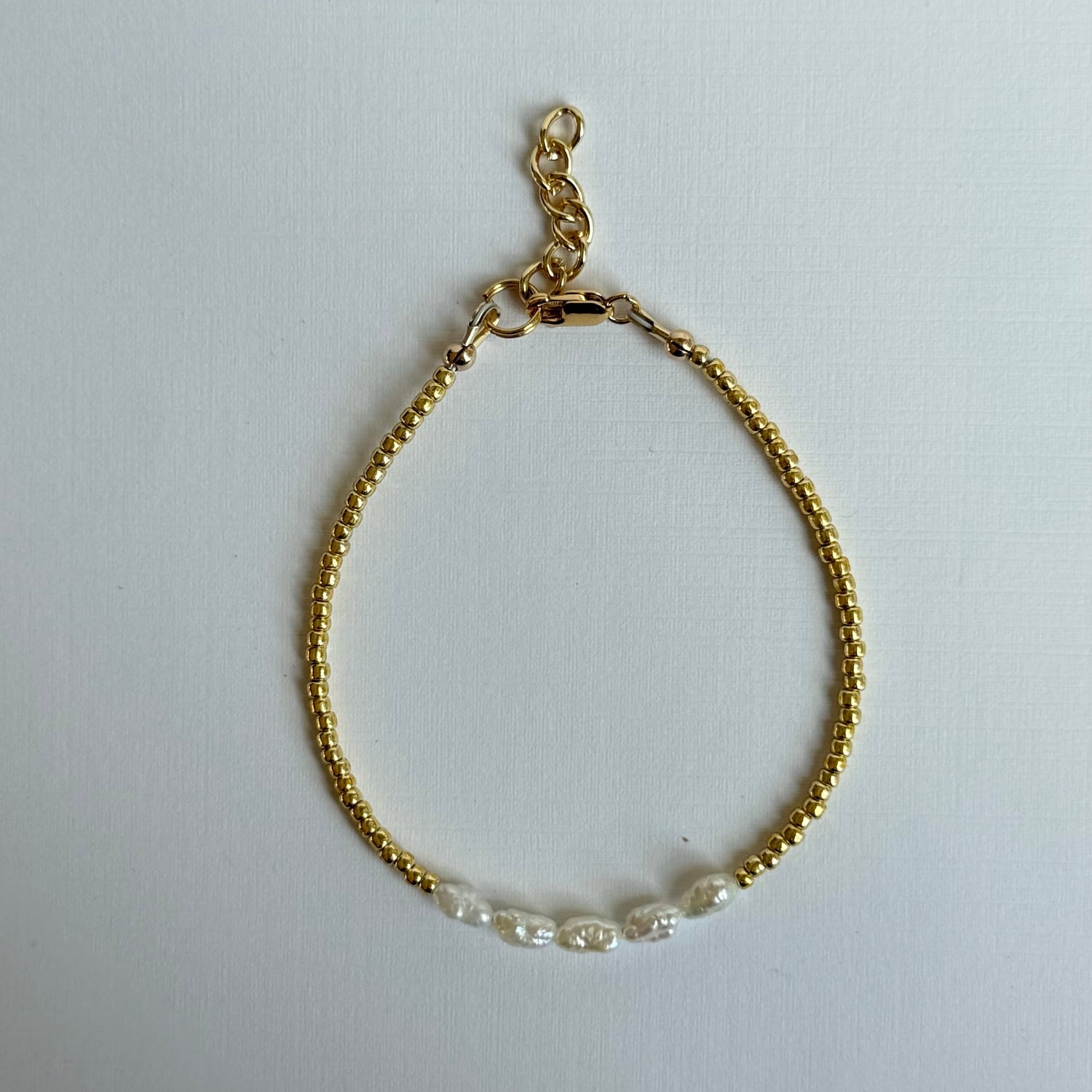 Gold bracelet with clear beads on a white background