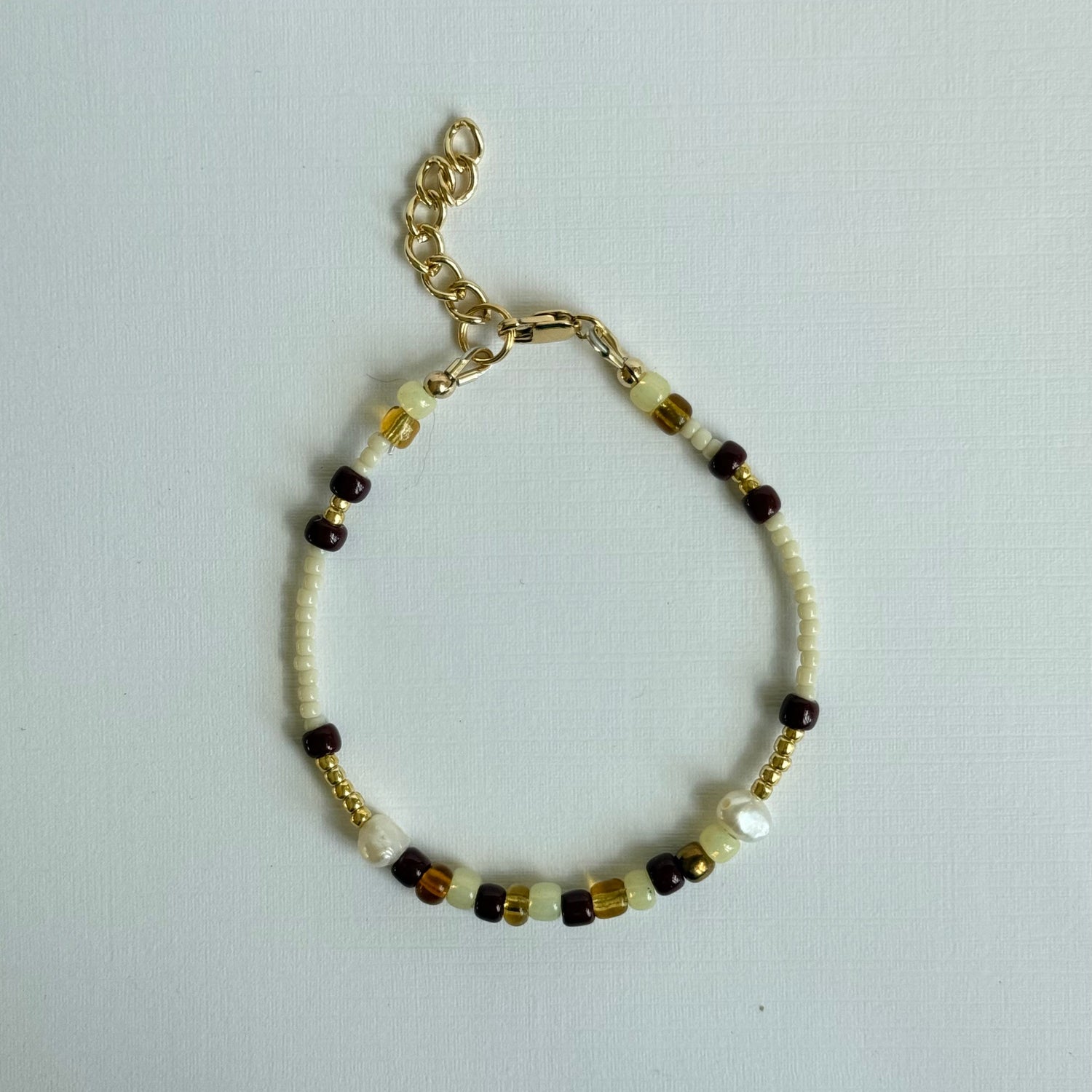 Beaded bracelet with gold chain on a light gray background