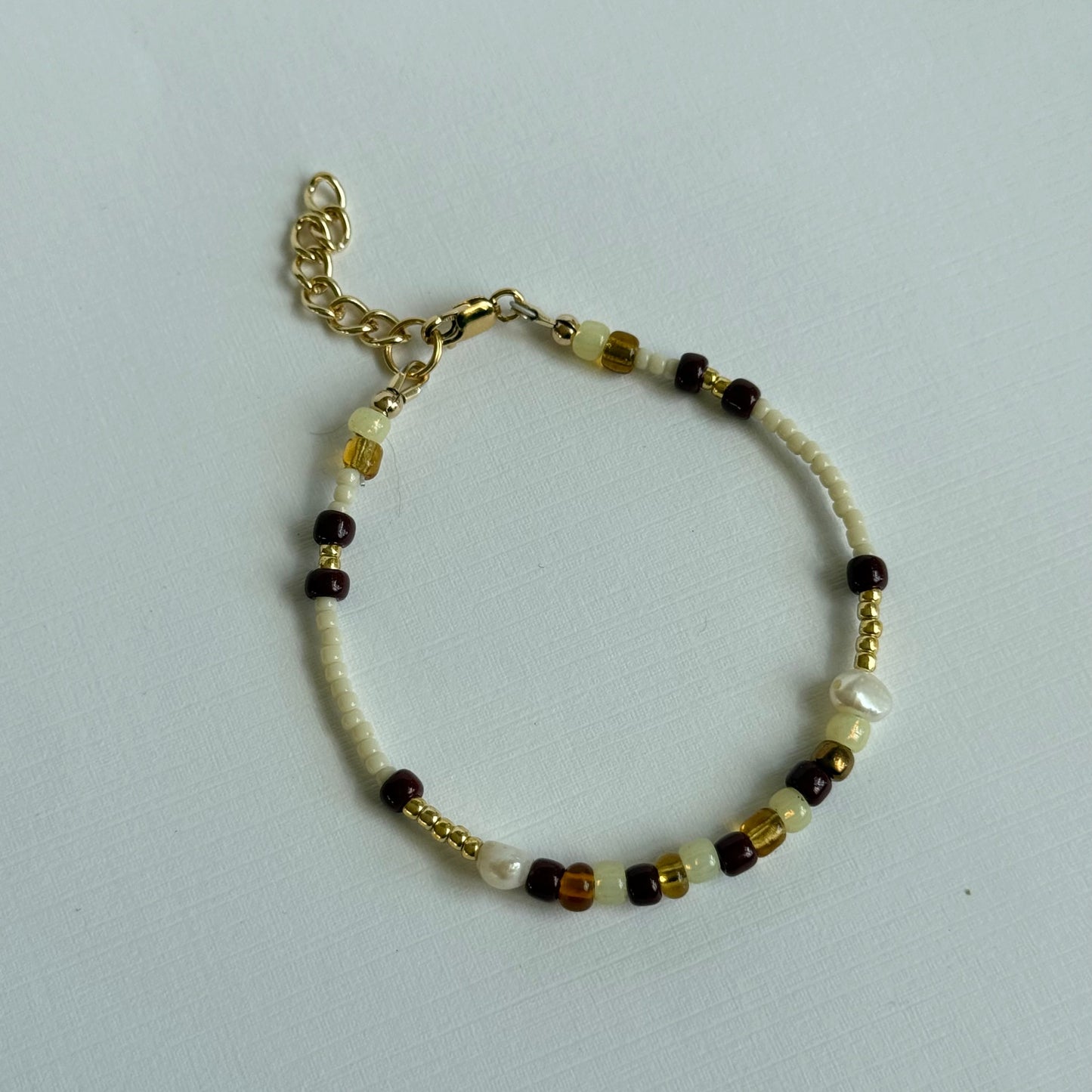 Beaded bracelet with gold chain on a light gray background