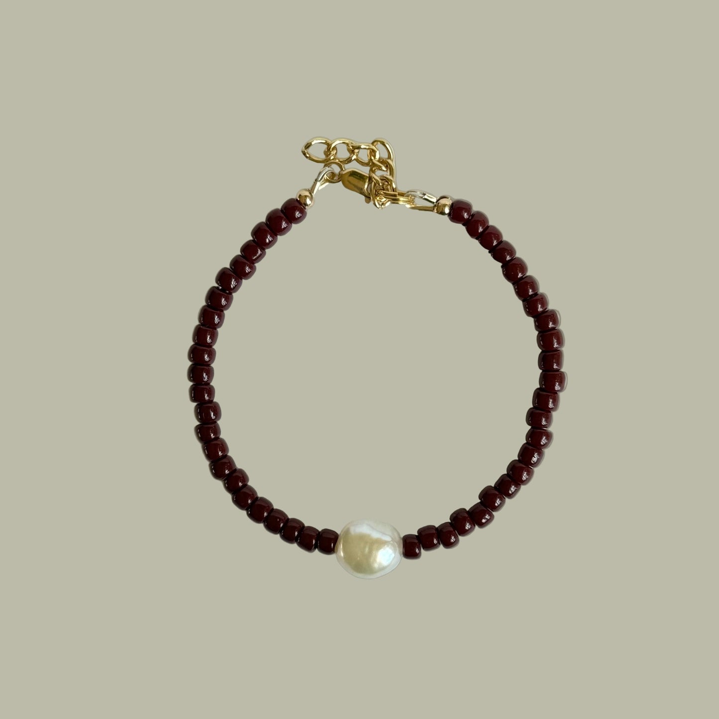 Bracelet with red beads and a pearl on a light gray background