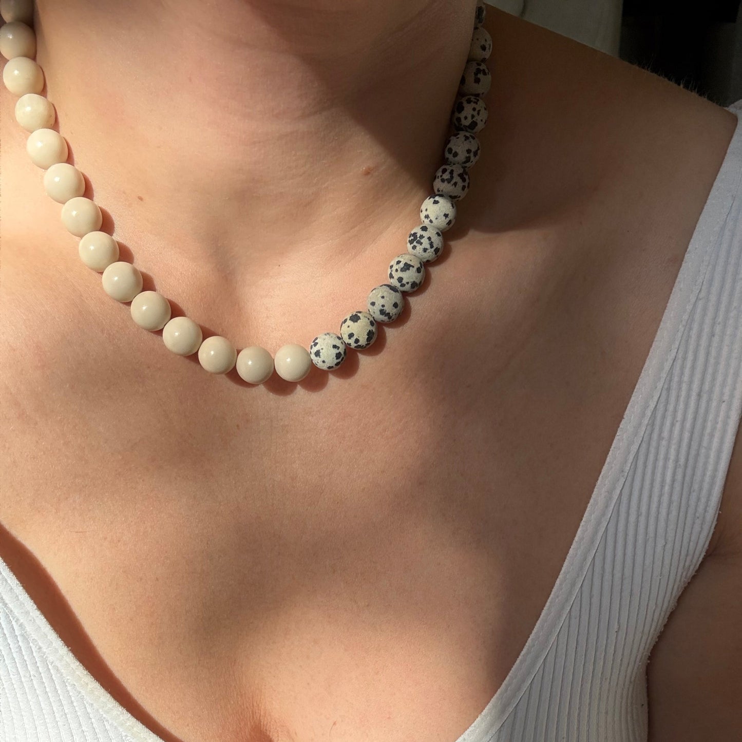 Close-up of a person wearing a white tank top with a necklace.