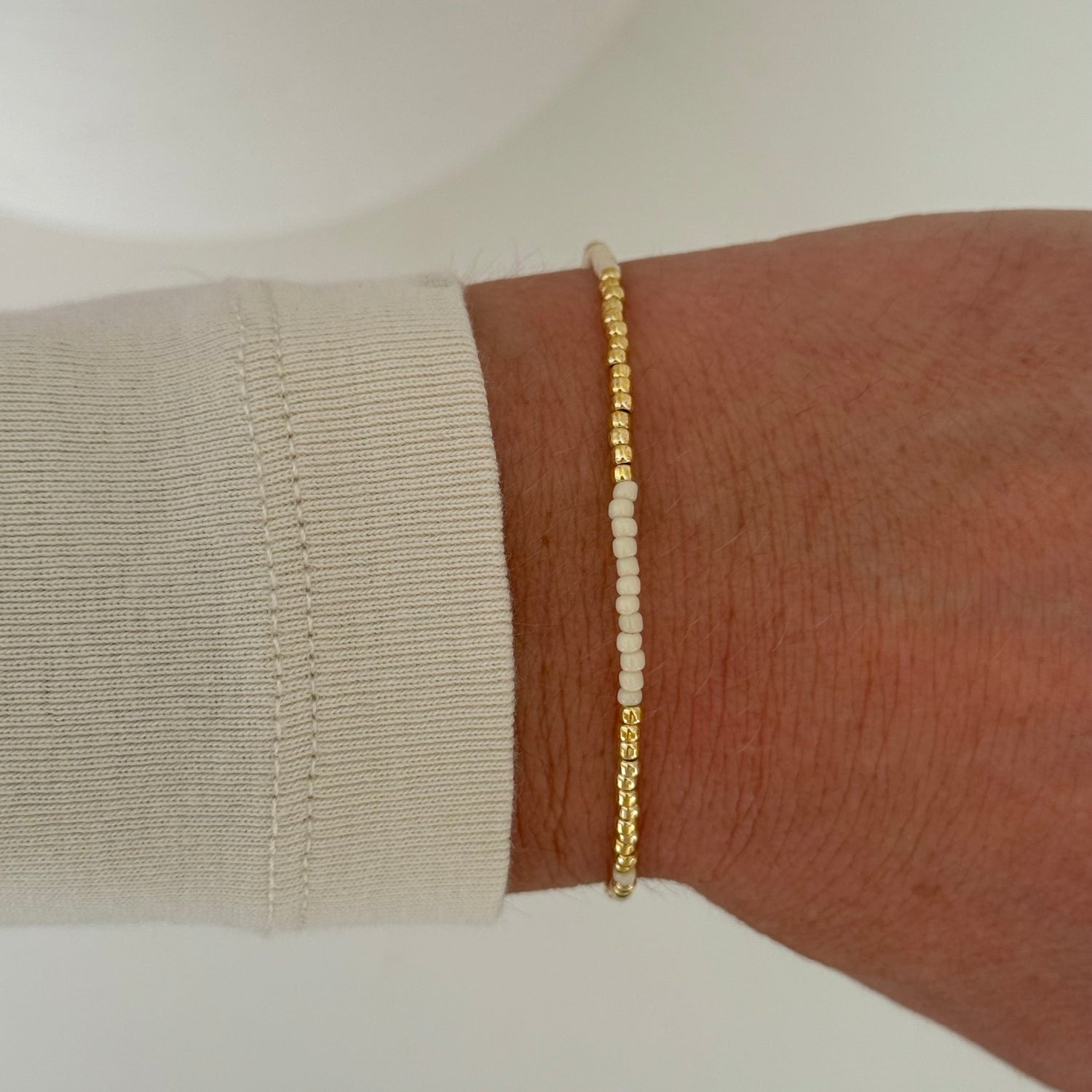 Gold bracelet on a wrist with a neutral background