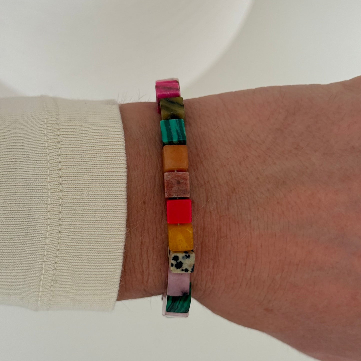 Multicolored beaded bracelet on a wrist with a plain background