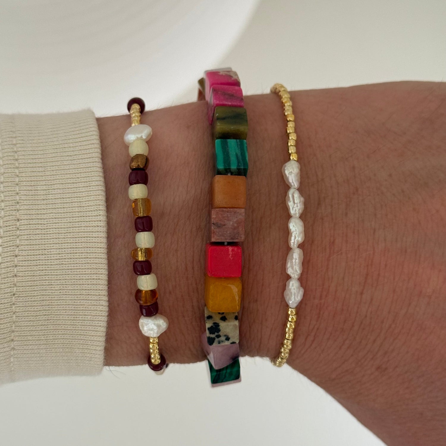 Three beaded bracelets on a wrist against a neutral background