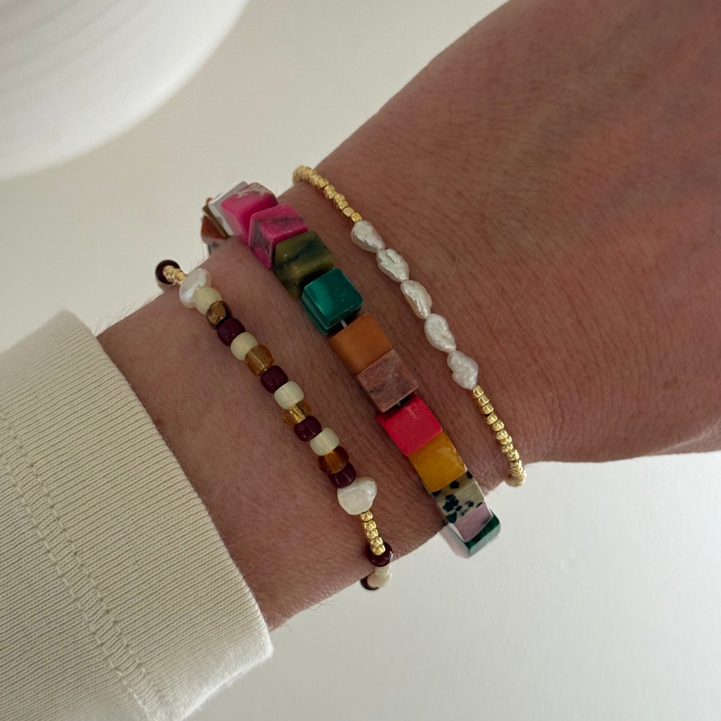 Close-up of a wrist wearing colorful beaded bracelets on a neutral background