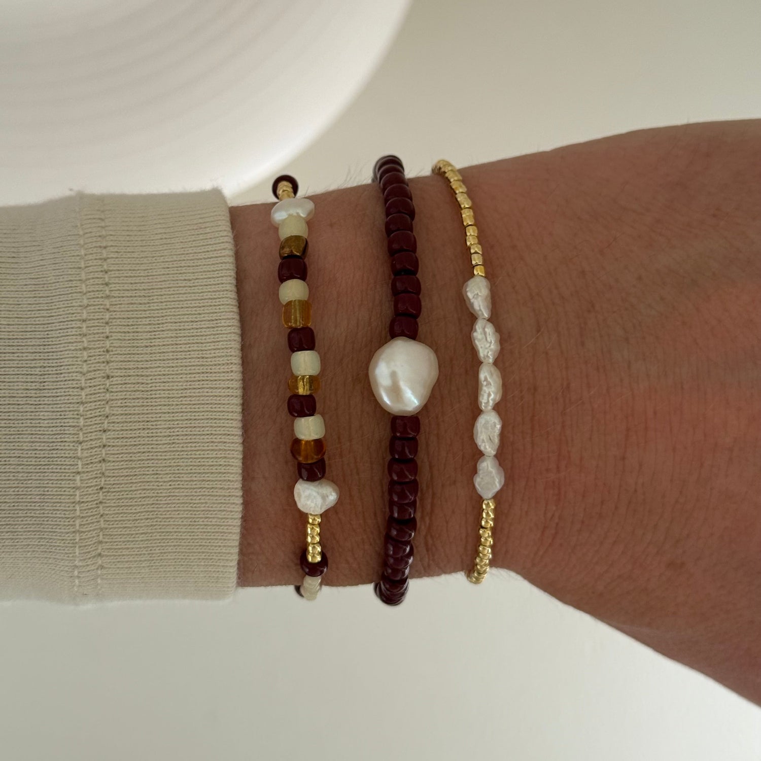Three beaded bracelets on a wrist against a neutral background