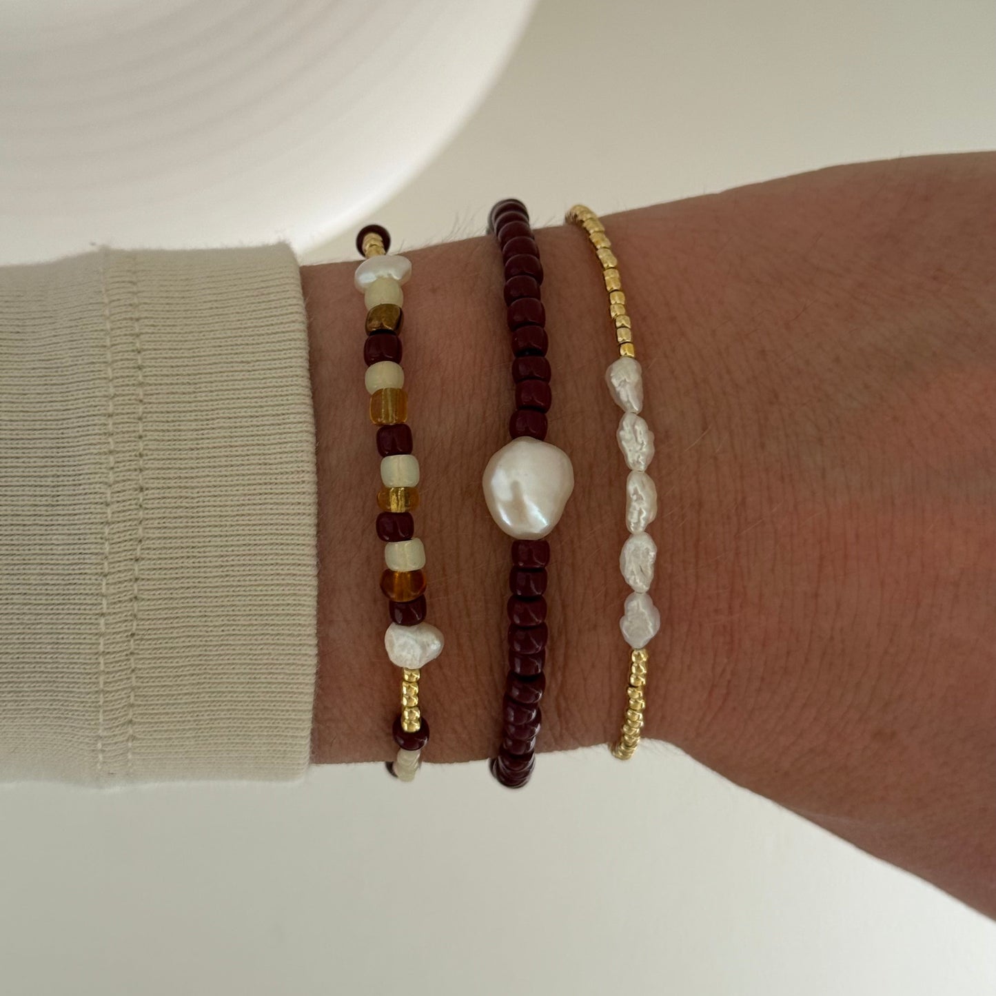 Three beaded bracelets on a wrist against a neutral background
