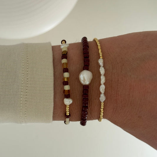 Wrist wearing four beaded bracelets on a neutral background