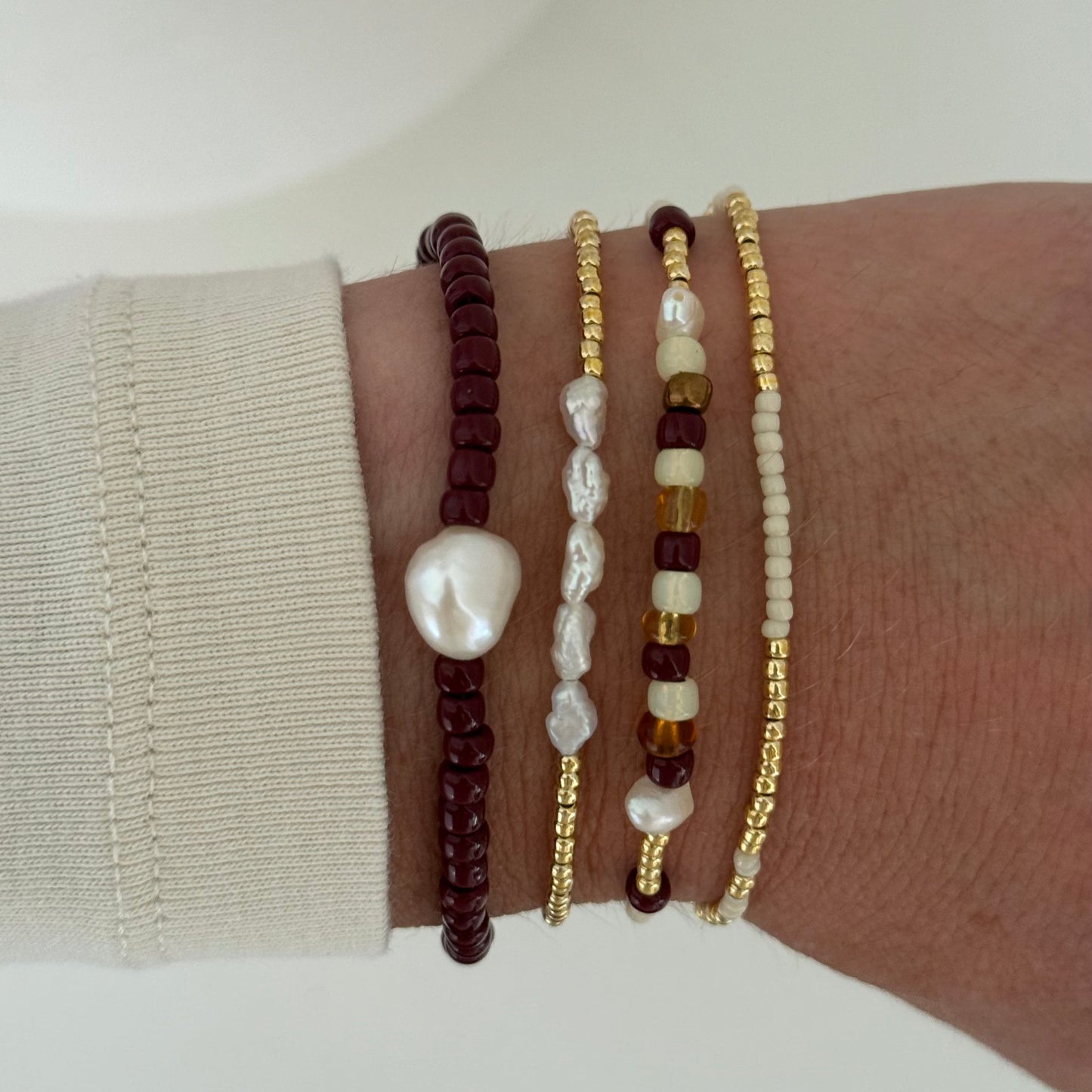 Three beaded bracelets on a wrist with a neutral background