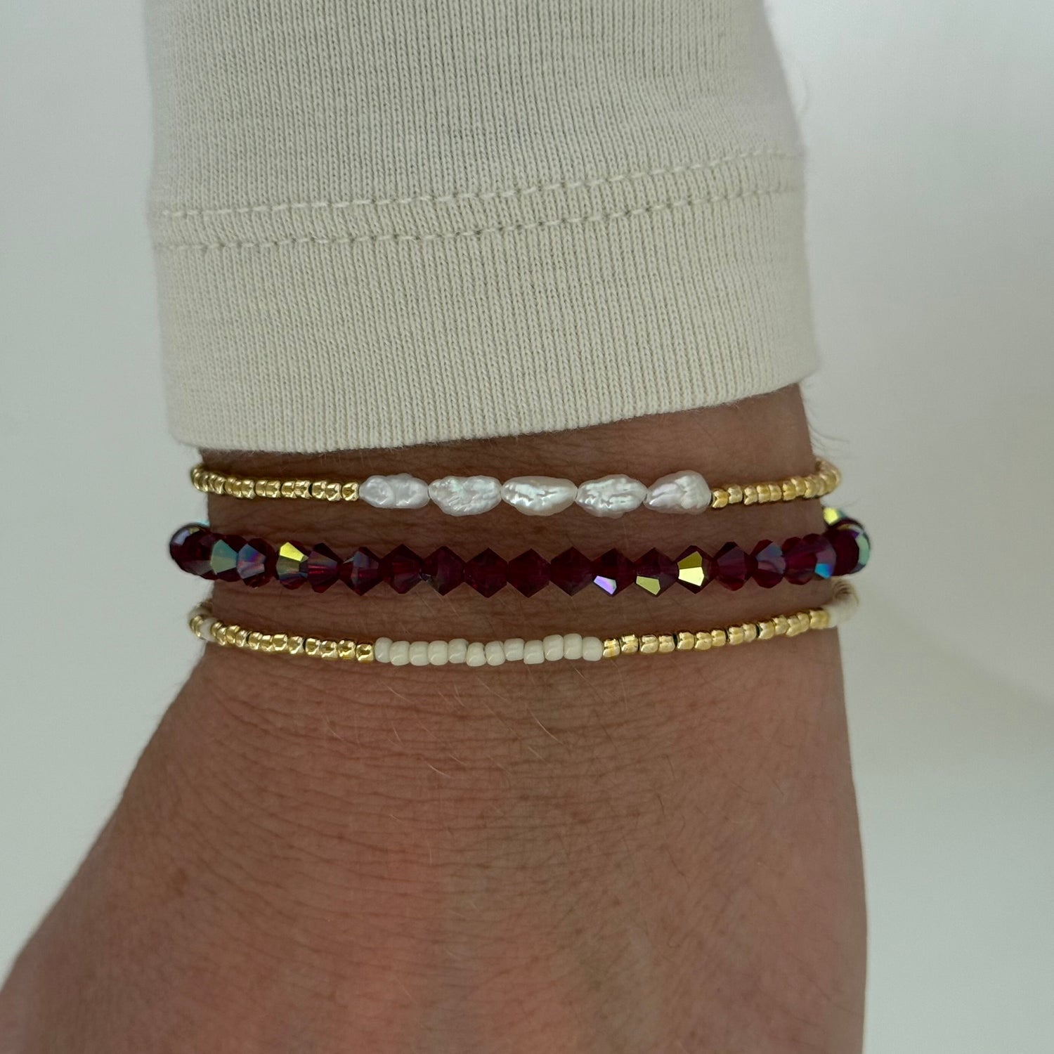 Close-up of a wrist wearing multiple beaded bracelets on a plain background