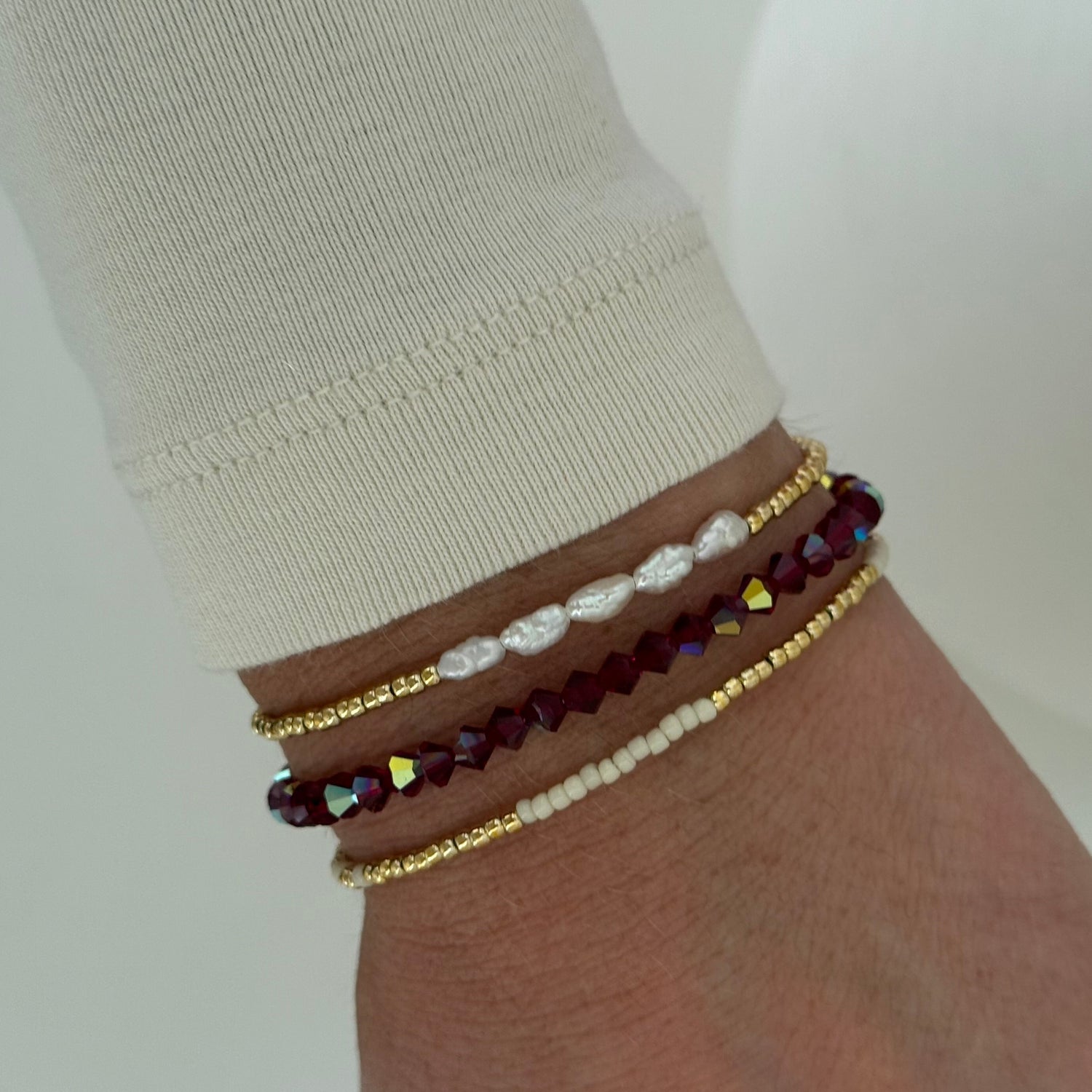 Close-up of a wrist wearing multiple beaded bracelets on a plain background