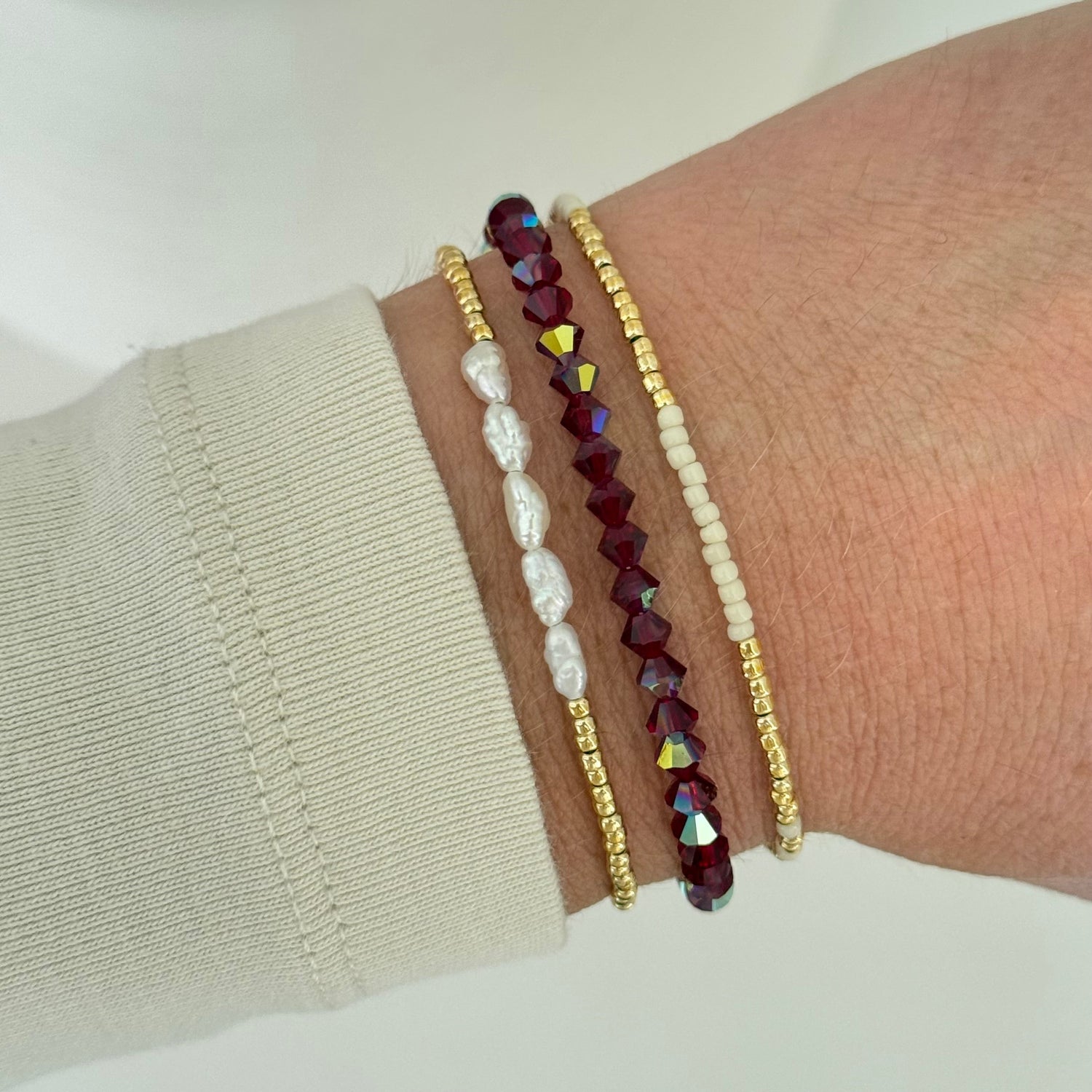 Close-up of a wrist wearing three beaded bracelets on a plain background