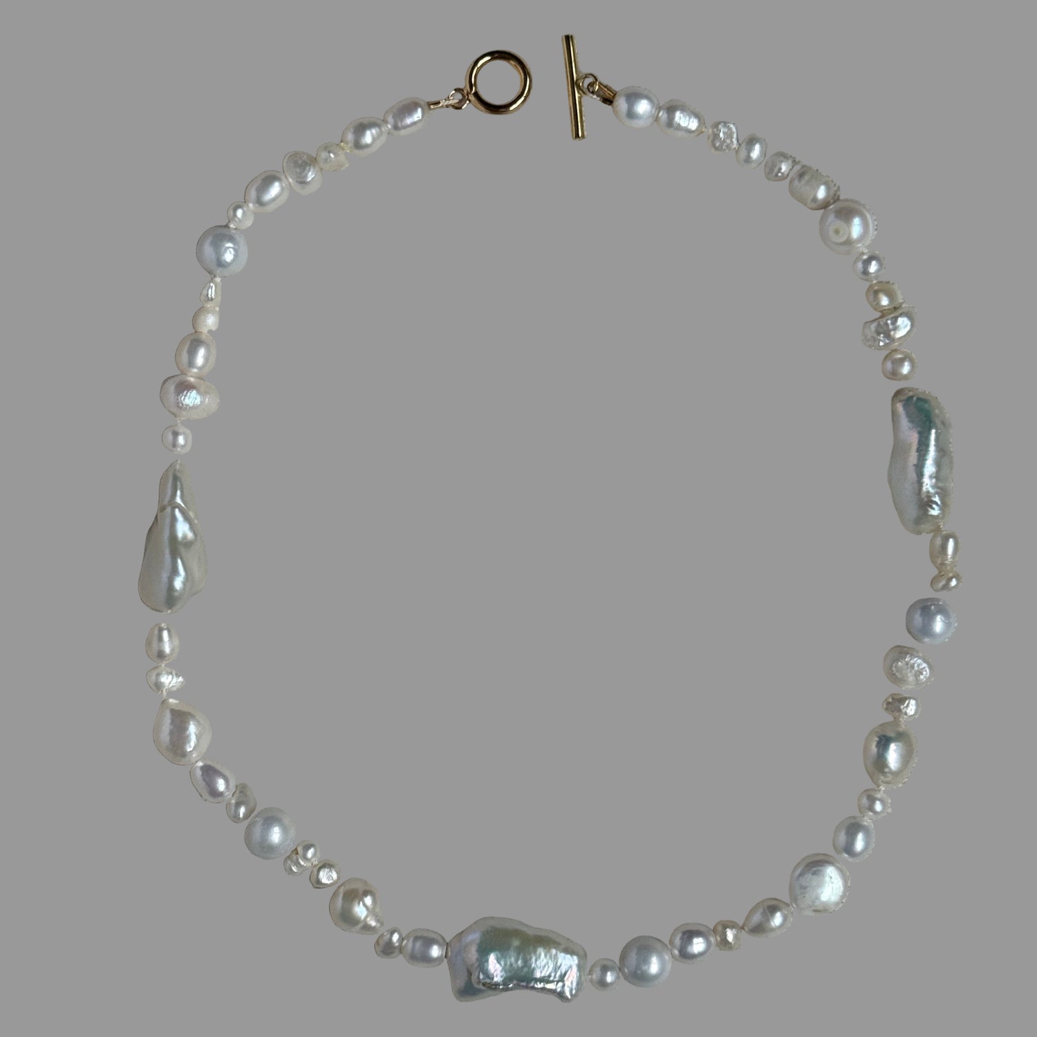 Pearl necklace with a clasp on a gray fabric background