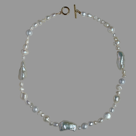 Pearl necklace with a clasp on a gray fabric background