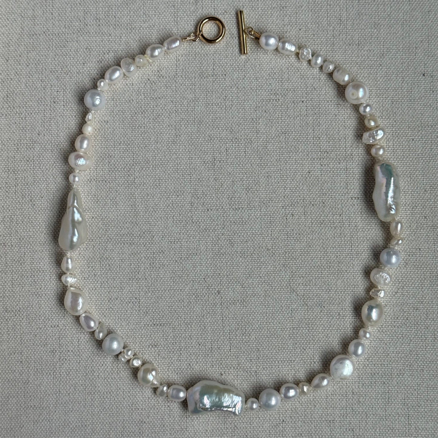 Pearl bracelet with silver clasp on a gray background
