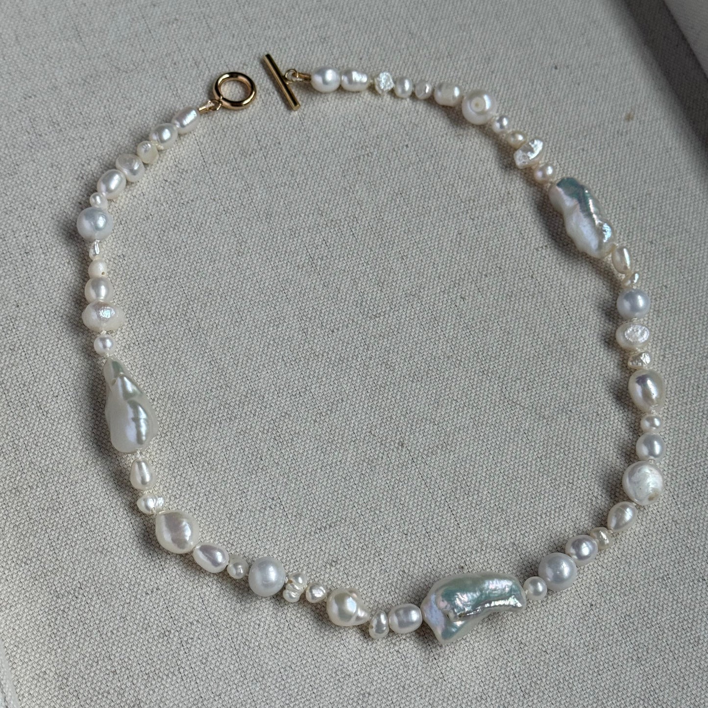 Pearl necklace  with gold clasp on a gray surface