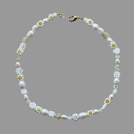 Necklace with white flowers and yellow centers on a gray background