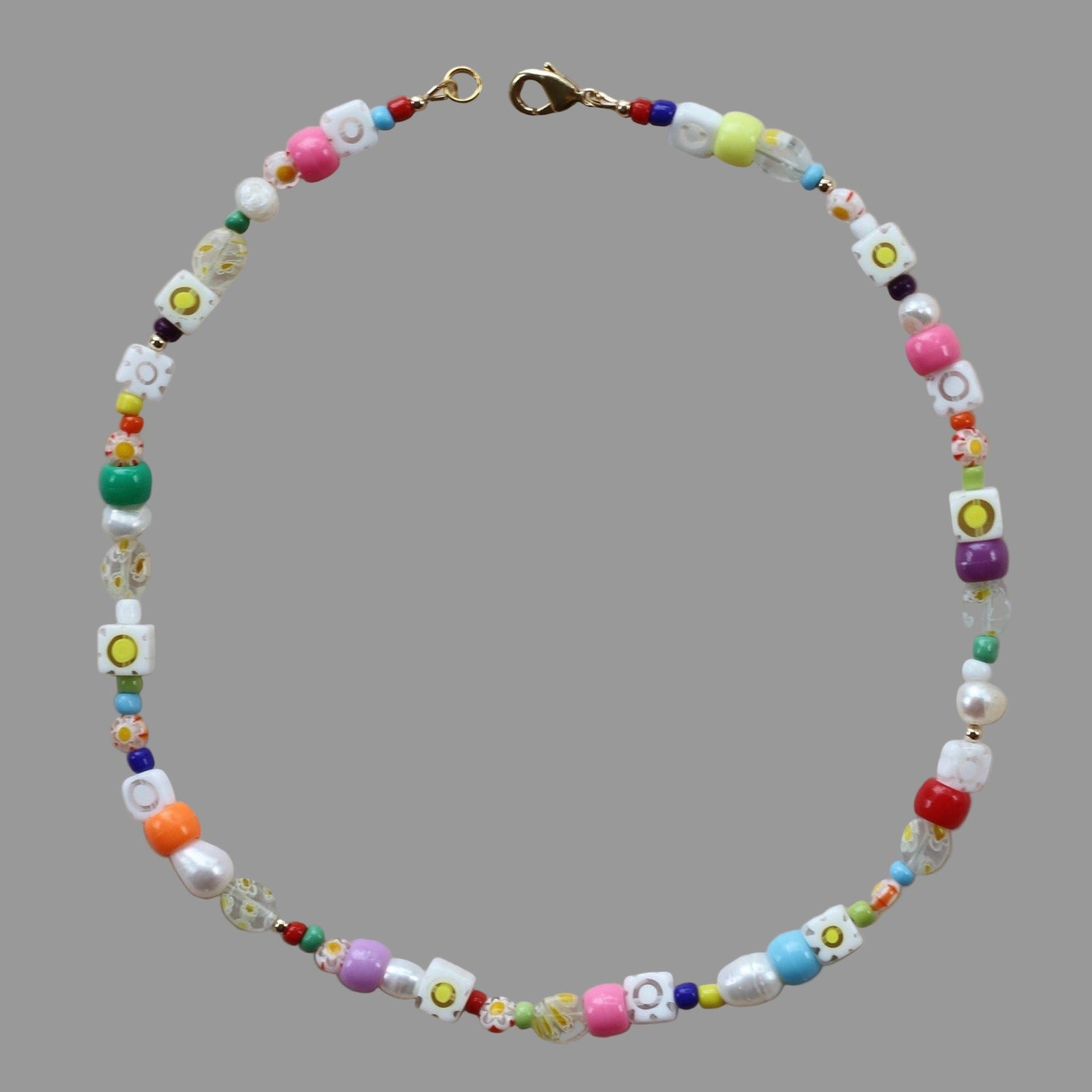 A colorful necklace with freshwater pearls, glass millefiori beads, and glass beads, featuring a gold-filled lobster clasp.