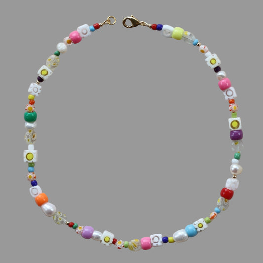 A colorful necklace with freshwater pearls, glass millefiori beads, and glass beads, featuring a gold-filled lobster clasp.