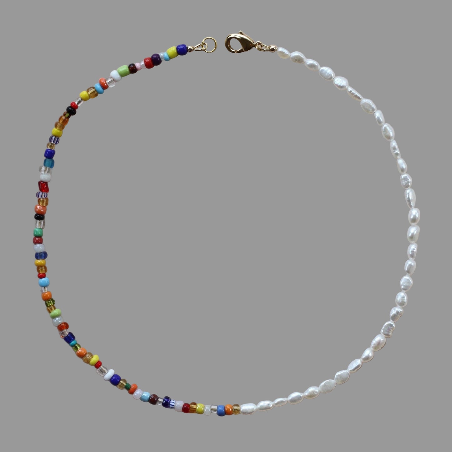 A colorful beaded necklace with freshwater pearls and a 14k gold plated clasp, displayed on a neutral background.