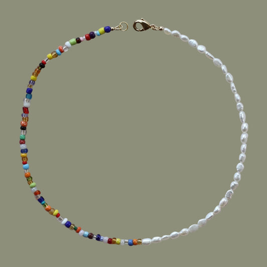 A colorful beaded necklace with freshwater pearls and a 14k gold plated clasp, displayed on a neutral background.