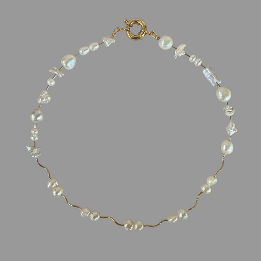 A gold-filled necklace featuring a series of freshwater pearls, some of which are baroque and keshi, with a gold-filled tube bead closure.
